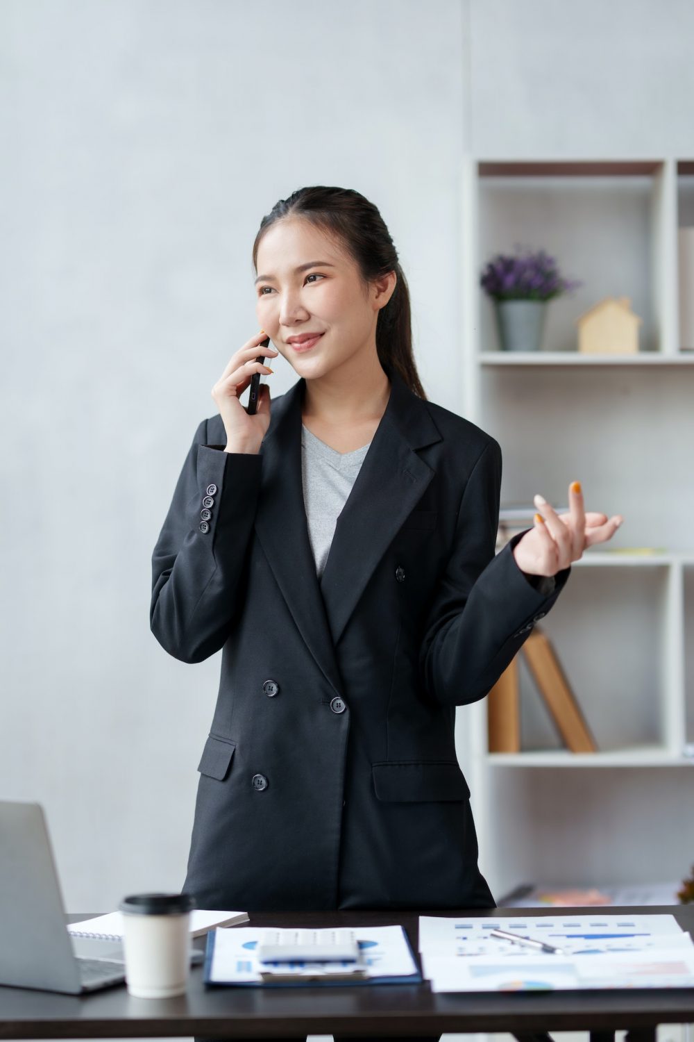 Smiling Asian businesswoman enjoying the phone, answering questions, talking to customers on the pho